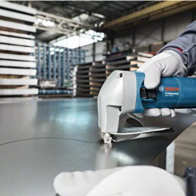 Furadeira azul Bosch Professional a perfurar chapa metálica preta numa fábrica