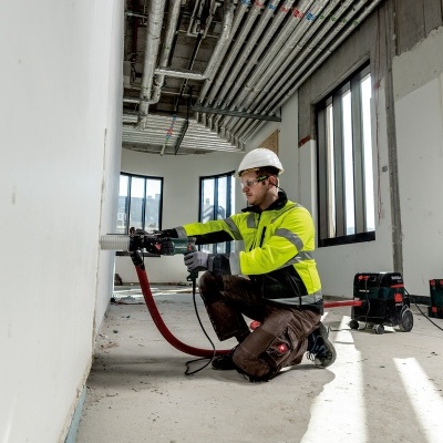Homem a trabalhar numa parede branca com ferramenta elétrica em construção interior