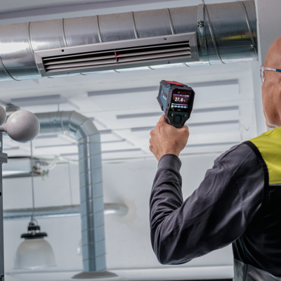 Homem a usar termómetro infravermelho para medir temperatura em ambiente industrial