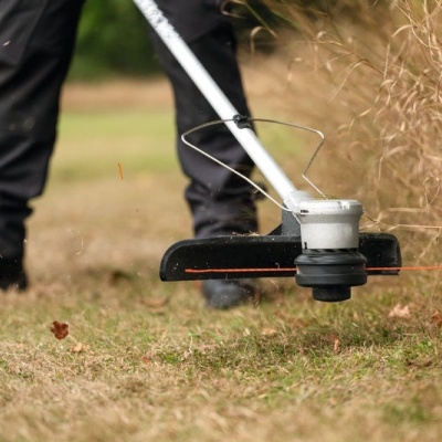Aparelho cortador de relva elétrico a cortar relva seca num jardim