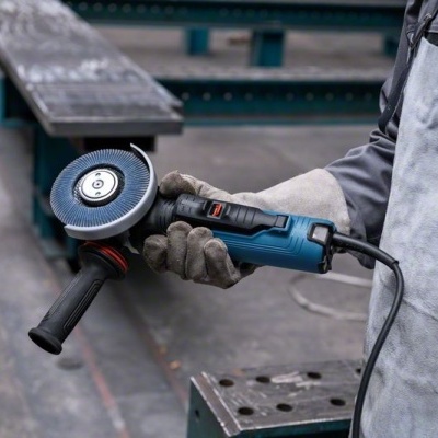 Pessoa segurando esmerilhadora elétrica azul e preta numa oficina