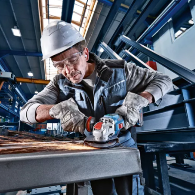 Trabalhador com rebarbador elétrico a desbastar peça metálica em fábrica