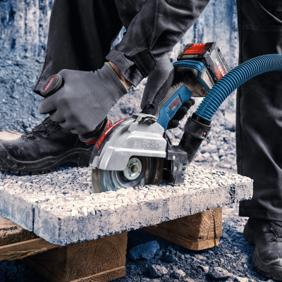 Operador usando cortadora angular Bosch para cortar placa de construção apoiada em paletes de madeira