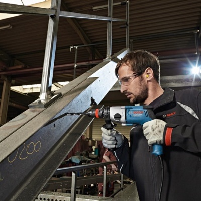 Homem a usar furadeira Bosch Professional numa estrutura metálica num ambiente industrial