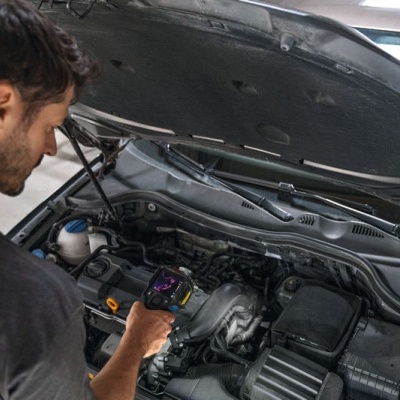 Homem a usar equipamento de diagnóstico automóvel num carro com capô aberto