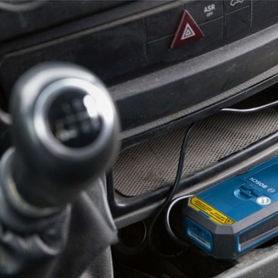 Alavanca de velocidades preta e dispositivo azul com etiquetas amarelas no interior de um carro