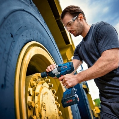 Homem usa chave de impacto em roda amarela ao ar livre