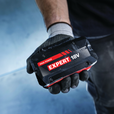 Bateria recarregável preta 18V segurada por mão enluvada