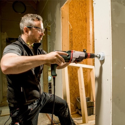 Homem a furar parede com furadeira elétrica