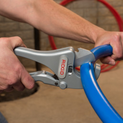 Ferramenta RIDGID cinza a cortar tubo azul em ambiente industrial