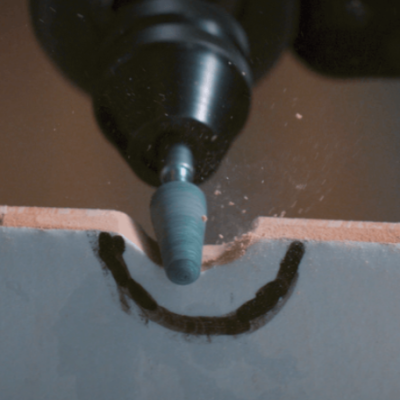 Ferramenta rotativa elétrica com ponta abrasiva a trabalhar numa madeira