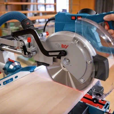 Serra de esquadria Bosch azul e preta a cortar madeira numa oficina