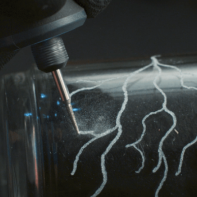 Mão com luva e ferramenta elétrica gravando padrão em vidro transparente