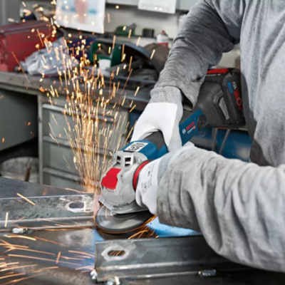 Pessoa a usar esmerilhadora elétrica a cortar metal com faíscas numa oficina