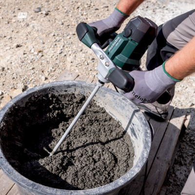Balde com cimento sendo mexido por batedeira elétrica