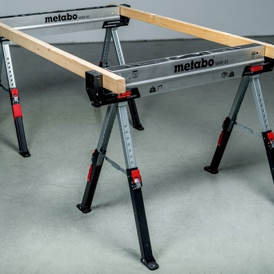 Mesa de trabalho metálica cinza com vigas de madeira claras e pernas pretas ajustáveis