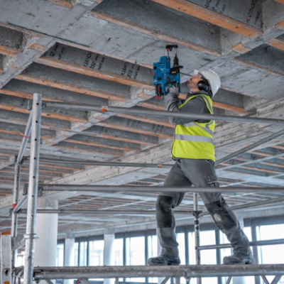 Trabalhador em andaime a usar ferramenta azul no teto