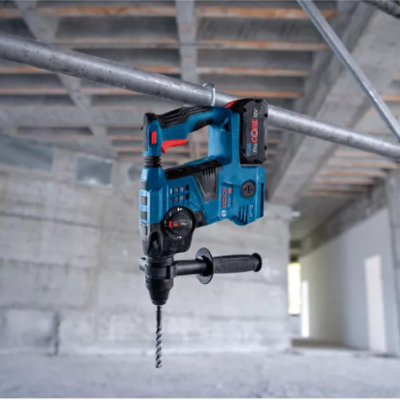 Martelo perfurador azul e preto suspenso num ambiente industrial de betão