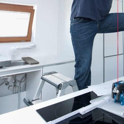 Medidor a laser Bosch numa cozinha moderna com balcão branco e placa de fogão embutida