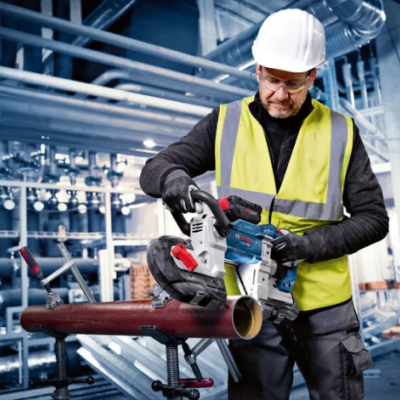 Homem a cortar tubo metálico com ferramenta elétrica no ambiente industrial