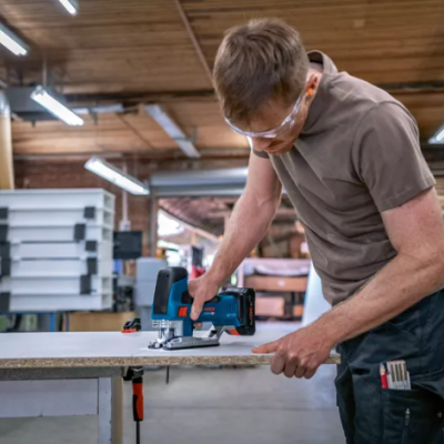 Homem a cortar madeira com máquina eléctrica numa oficina