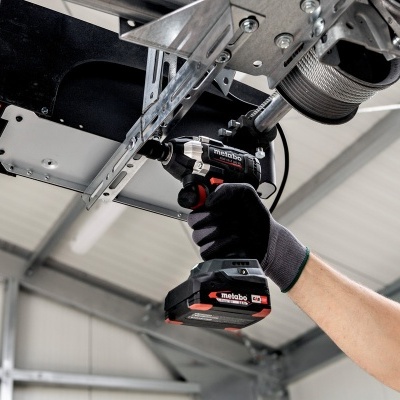 Pessoa a usar ferramenta elétrica Metabo para aparafusar estrutura metálica no teto