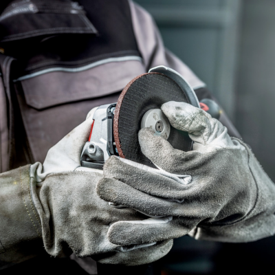 Profissional segurando esmerilhadora angular com disco abrasivo em ambiente industrial