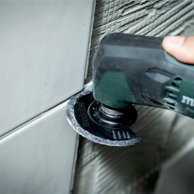 Ferramenta eléctrica Metabo a cortar azulejos brancos numa parede