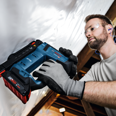 Homem a usar pistola de pregos Bosch numa estrutura de madeira