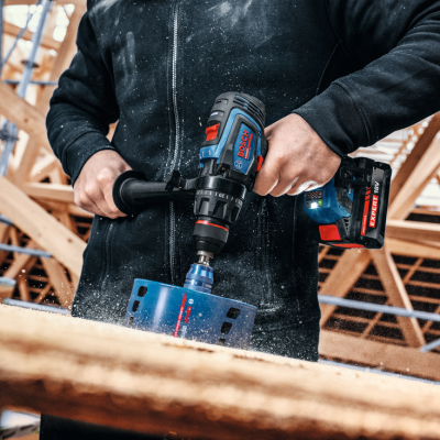 Impressora Bosch a bateria a perfurar madeira numa construção interior.