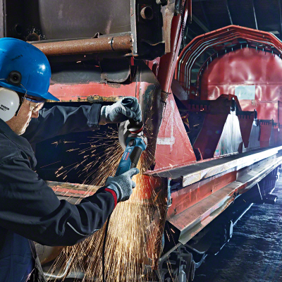 Trabalhador com rebarbadora Bosch a cortar metal vermelho em ambiente industrial