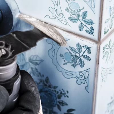 Aplicação de selante branco em azulejos brancos com padrão azul com pistola de selante