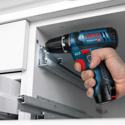 Parafusadeira Bosch Professional 12V a ser usada num móvel branco.
