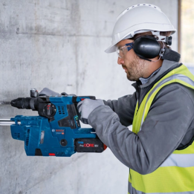 Homem com colete refletor usando furadeira Bosch na construção