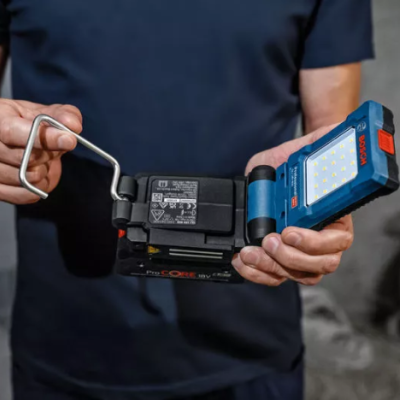 Dispositivo Bosch azul com detalhes vermelhos e pretos segurado por uma pessoa