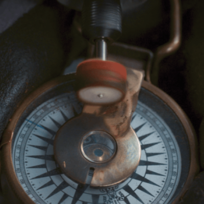 bússola metálica envelhecida a ser polida com disco abrasivo em mão de luva preta