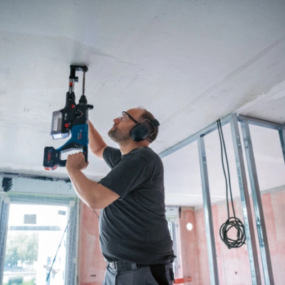 Homem a usar ferramenta elétrica azul no teto em obra