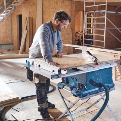 Homem a cortar madeira com serra circular numa oficina de carpintaria