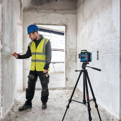 Homem com colete e capacete a medir parede numa construção