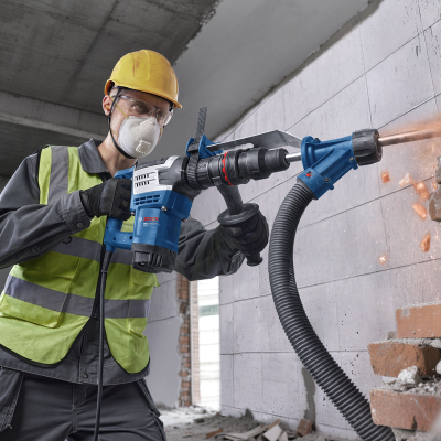 Homem a usar ferramenta elétrica Bosch para perfurar parede de tijolos
