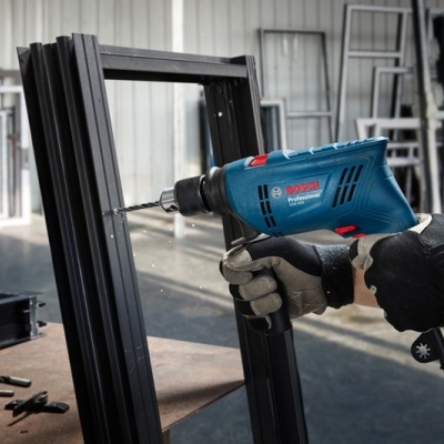 Máquina de furar elétrica Bosch Professional a trabalhar numa estrutura metálica preta numa oficina