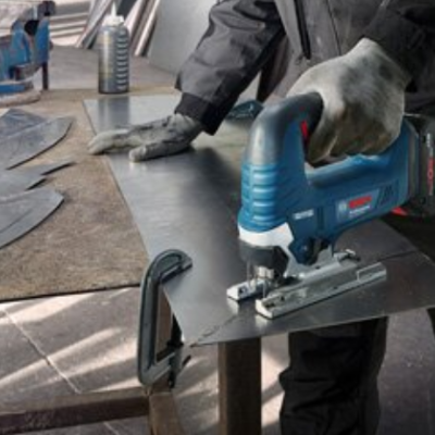 Máquina de corte elétrica a cortar chapa metálica numa mesa de trabalho em oficina