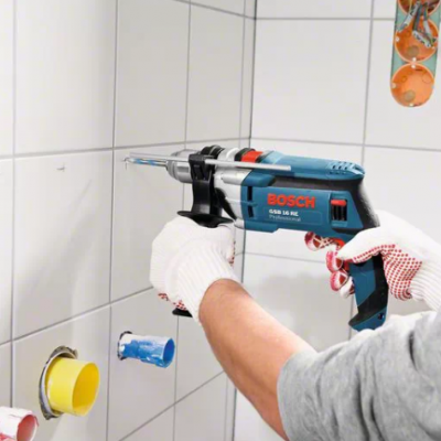 Furadeira Bosch azul e preta a perfurar azulejo branco na parede