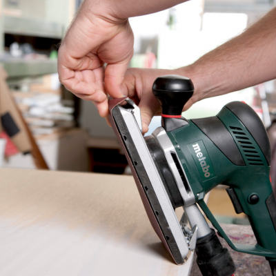 Lixadeira elétrica Metabo verde e preta numa oficina