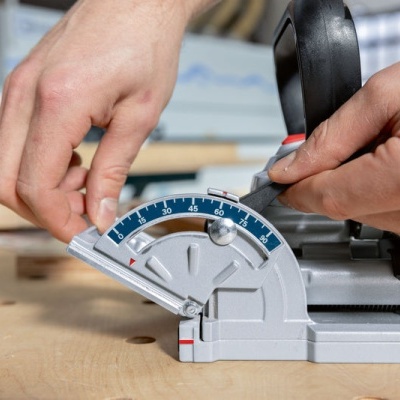Serra de esquadria cinza com escala azul a medir corte numa peça de madeira