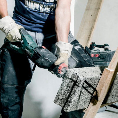 Pessoa a cortar bloco de cimento com ferramenta elétrica num ambiente de construção