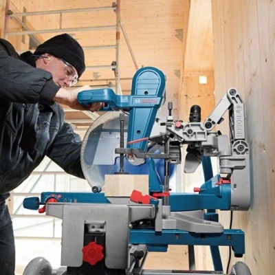 Serra de corte azul e cinzenta em estrutura de madeira clara com operador vestido de preto