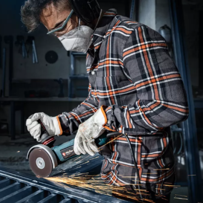Homem com máscara e óculos a usar esmeril elétrico numa oficina