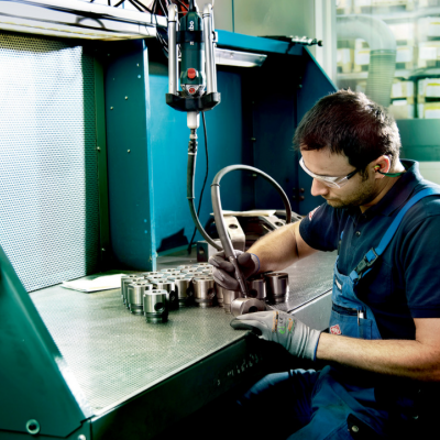 Homem a trabalhar peça metálica numa máquina industrial