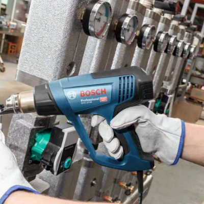 Ferramenta Bosch Professional GHG 660 LCD numa oficina com mãos luvas a segurá-la